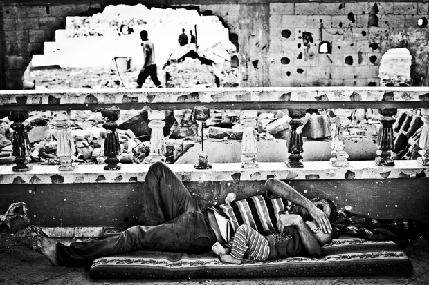 Gaza, Beit Hanoun: Abdel Abu Ouda,  and his son are resting in the living room of their house half destroyed during the bombing of summer 2014.
