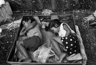 Children sleep behind the stall where their parents sell fresh vegetables in Khlong Toei market, Bangkok 2107