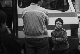 A boy with his dad at the bus station.