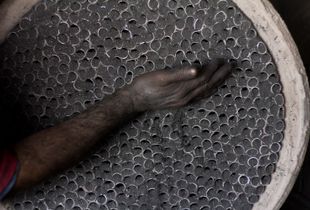 Gerardo's hand filling paper  tubes with powder as a process to create firecrakers.