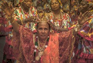 Master Bita is crowned by three Terecô priestesses during a spiritual celebration.
