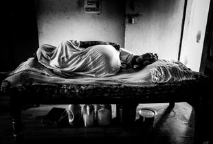 Ashram Chaitanya Vihar: a widow rests in her bed over her belongings. The only ones she have.