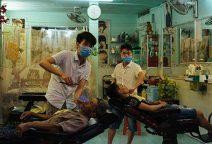 Masked barbers providing a cut and shave.