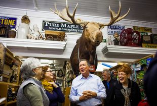 Republican presidential candidate Gov. John Kasich (center) of Ohio talks with a group of women after posing for a photo with them under a mounted moose at Fadden's General Store in North Woodstock during a campaign bus tour through New Hampshire on Wednesday, Oct. 14, 2015.