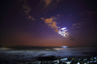 Stardust/Seascape at twilight: the Atlantic Ocean from the coast at Kommetjie, South Africa, with the moon hiding behind some clouds.
