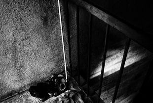 Light in the Abyss / Abby sticks and shoes are neatly arranged at the entrance of his house.