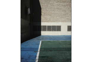 Empty non-residential schoolyard under the sun hitting the wall.