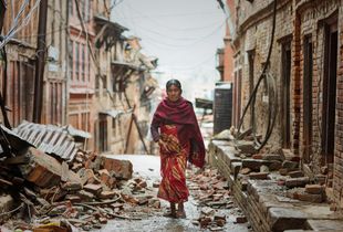 A woman walks through the rubble of homes destroyed during the 2015 Nepal earthquake.