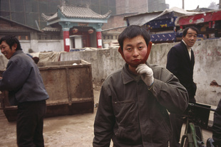 Workers return the gaze of the Lowai (stranger) photographer, the red wool ear muffs are traditionally worn by manual labourers.  Xi'an, China. 22 December 2006.