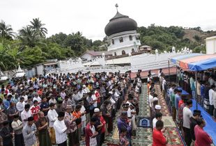 Survivors perform Friday mass prayer outside a collapsed Jami Quba Mosque following the earthquake in Pidie Jaya, Aceh province, on December 9, 2016.