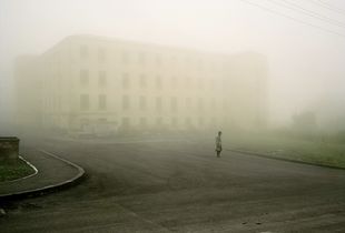 UNRECOGNIZED REPUBLIC OF NAGORNO-KARABAKH / Shushi / 29.8.2011. A man walks across the street in the fog in front of a war ruin. In Shushi even today many ruins still give evidence of the war which almost completely destroyed the two cultures: the Shiite Azeris and the Christian Armenians, a town which formerly was a symbol of friendly cohabitation.