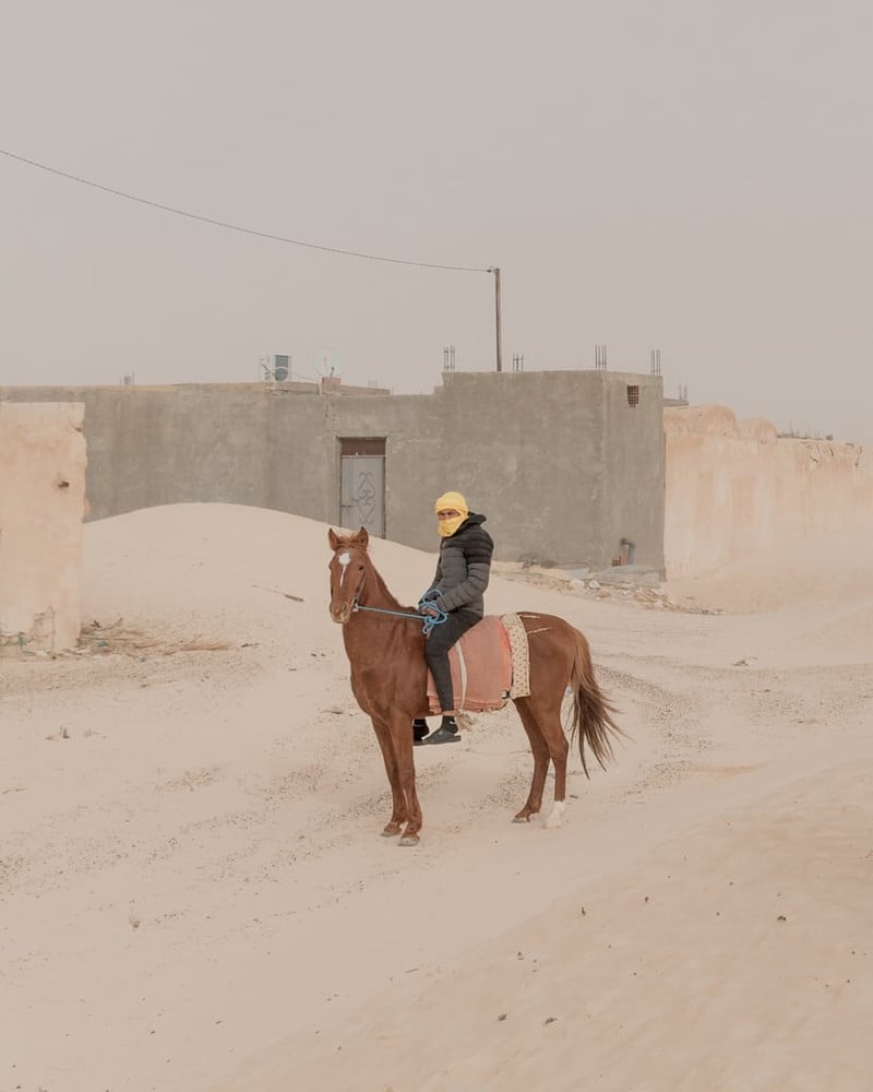 Portrait of Resilience. A rider in Sabria, Tunisia, stands for a portrait amidst the town’s landscape, where sand encroachment steadily reshapes the environment, challenging the local community. © Skander Khlif