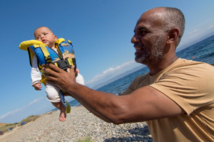 A refugee from Syria holds a baby just after reaching the shore at Lesvos island. More than 800,000 refugees have crossed form Turkeyduring 2015. August 22, 2015, Lesvos, Greece