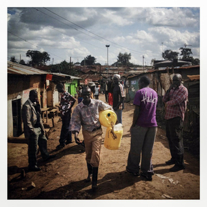 A young man carries water canisters through Kibera. The Kibera slum is the largest slum in Nairobi with around half a million inhabitants.