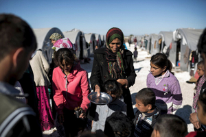 A Syrian Kurdish woman waits for a food at 'Arin Mirhan' refugee camp in the border town of Suruc, Sanliurfa province on November 5, 2014.