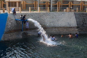 Kids playing on the big pipe where the water is pumped in the pool