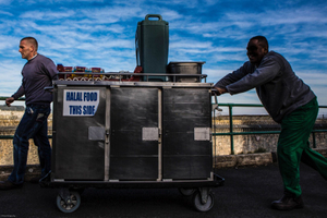 Prisoners transport food in special containers and bread crates from the main kitchen through the prison to a wing to be served.  HMP/YOI Portland, Dorset.
