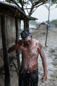 A man trying to shower in the rain but it has been stopped suddenly.