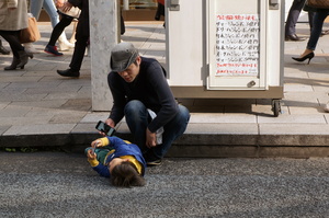 infant playing game on handheld game console lying on street