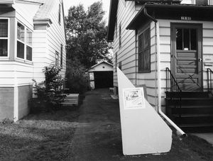 "Garage Interiors" installation (sidewalk view with poster on drywall 'welcome mat'), Madison, WI, June 1983