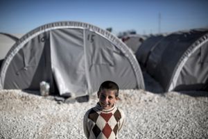 A Syrian Kurdish boy poses for a photo in front of a tent at 'Arin Mirhan' refugee camp in the border town of Suruc, Sanliurfa province on November 5, 2014.