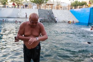 Man is checking his watch for the time after a good swim