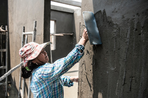 Meng Chan 38 from Prey Veng Province skims the walls of a newly constructed house with concrete. Chan has been working in construction for 2 years now. Chan believes she works as hard as the men and also has the same skills as the male workers.