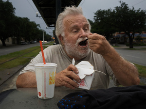 USA. New Orleans. 2015. Portrait of a homeless eating fast food.