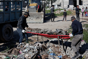 A group of Kurdish people from a committee which was found after the liberation of Kobane to oversee the  clean-up operation, remove the remains of Islamic state fighter on 25 April 2015