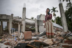 Survivor, Saprina Rajali, 30 years old, grieving as she visit her collapsed house that killed her mother following the earthquake in Pidie Jaya, Aceh province, on December 11, 2016.