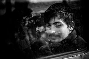 Young man looking through the window of the old train carriage, which is his temporary shelter at the back of main train station in Belgrade, Serbia.