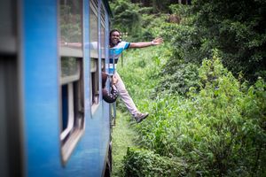 A passenger posing photo for his friend in a moving train.