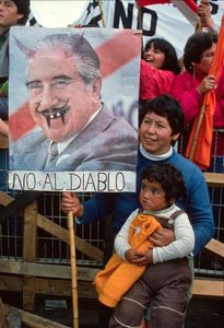 Mother and child with an anti-Pinochet  poster saying 'No to the Devil' during the 'NO' referendum campaign in 1988. Santiago, Chile,