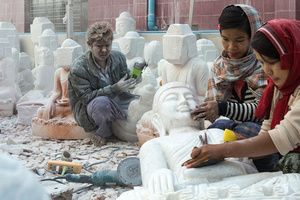 Workers grind and polish statues of Buddha at workshop in Mandalay.