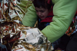 A young boy cries after making the crossing from Turkey in an inflatable boat. Volunteers and rescuers take care of refugees who landed at the shores of Mytilene, the capital of Lesvos island. More than three hundred refugees landed on the shores of Lesvos on a single day. March 13, 2016, Lesvos, Greece.