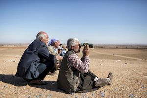 Kurdish men watch the fighting in Kobani, from the Mursitpinar village on the outskirts of the Turkey-Syria border on November 5, 2014.