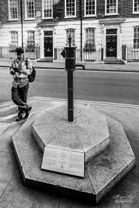 Man pausing by water pump in Soho