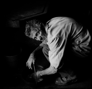 Farmer Castella cleaning the fire-pot in his kitchen