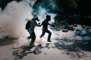 A protester kicks a tear gas canister back towards police lines during a stand-off between anti-Government protesters and police at Government House in Bangkok.