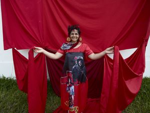Gauchito Gil devotee happy wrapped in the red coloured flags of the popular saint and wearing earring with the saint icon in the El Yaguarì estancia in Curuzù Cuatià village