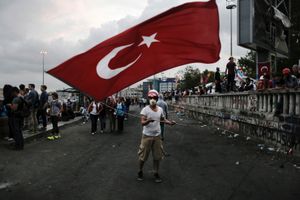 A protester with a gas mask waves a large Turkish flag during demonstration in Taksim square in Istanbul on Thursday June 13, 2013.