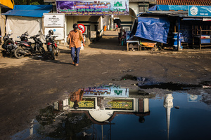 A Minaret of one of the many mosques in Jakarta reflects in a puddle of water