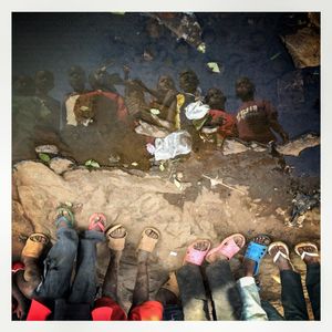 Children are reflected in a puddle in Kibera. The Kibera slum is the largest slum in Nairobi with around half a million inhabitants.