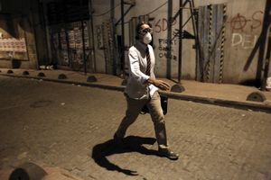 A well dressed man with gas mask walks near Taksim square during massive night clashes between demostrators and riot police in Istanbul, Turkey on Tuesday, June 11, 2013.