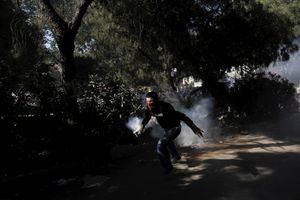 A protester wears a kerchief over his face trying to remove a tear gas canister through the Gezi park during clashes near Taksim Square in Istanbul, Turkey on Tuesday, June 11, 2013.