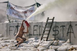 A protester dressed only in underpants sprays a fire extinguisher over barricades towards police lines during a stand-off between anti-Government protesters and police at Government House in Bangkok.