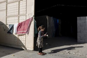 A Kurdish girl from Kobani cleans an onion inside a factory used as refugee camp, known as Suphi Nejat Agirnasli in the town of Suruc, Sanliurfa province, Turkey on November 9, 2014.