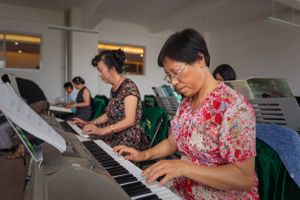 A woman learning to play the piano on an electronic keyboard during a class at a University of the Third Age (U3A).