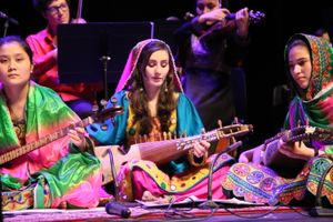 Girls on the stage with traditional afghans instruments and clothes.