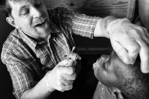 Sometimes actions do speak louder than words. Although Dr Keith has an excellent working knowledge of Swahili, here we see him showing his young patient what to do: fungua mdomo (open your mouth).                © Lola Reid Allin